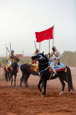Essaouira, Fas - 13 Ağustos 2023: Biniciler geleneksel Fas kıyafeti ve şövalyelerin aksesuarları içinde Arapça Tbourida adlı geleneksel bir giysi etkinliğine katılıyorlar