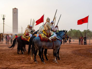 Essaouira, Fas - 13 Ağustos 2023: Biniciler geleneksel Fas kıyafeti ve şövalyelerin aksesuarları içinde Arapça Tbourida adlı geleneksel bir giysi etkinliğine katılıyorlar