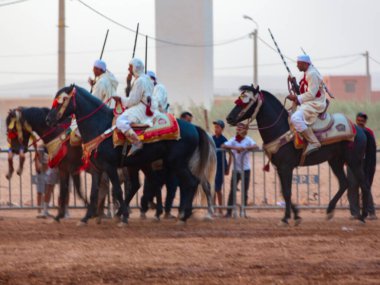Essaouira, Fas - 13 Ağustos 2023: Biniciler geleneksel Fas kıyafeti ve şövalyelerin aksesuarları içinde Arapça Tbourida adlı geleneksel bir giysi etkinliğine katılıyorlar