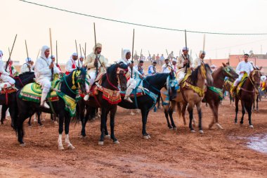 Essaouira, Fas - 13 Ağustos 2023: Biniciler geleneksel Fas kıyafeti ve şövalyelerin aksesuarları içinde Arapça Tbourida adlı geleneksel bir giysi etkinliğine katılıyorlar