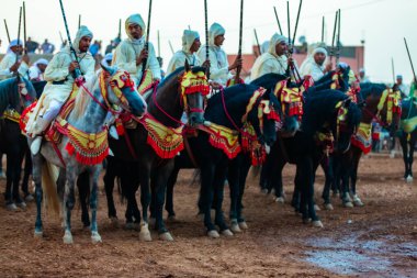 Essaouira, Fas - 13 Ağustos 2023: Biniciler geleneksel Fas kıyafeti ve şövalyelerin aksesuarları içinde Arapça Tbourida adlı geleneksel bir giysi etkinliğine katılıyorlar
