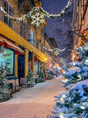 Kış ve kar yağışları sırasında Sihirli Petit-Champlain Caddesi, tatil süslemeleriyle aydınlatılmış, Kuzey Amerika 'nın en eski ticari caddesi, Eski Quebec Şehri, Kanada. Fotoğraf Aralık 2020 'de çekildi..