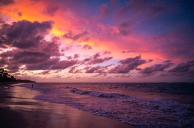 Bavaro Sahili ve Atlantik Okyanusu üzerinde gün batımı dramatik ve renkli günbatımı alacakaranlığı, kıyılara vuran dalgalar, palmiye ağaçları silueti, Punta Cana, Dominik Cumhuriyeti, Karayipler. Fotoğraf Nisan 2022 'de çekildi..