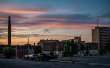 Colourful sunset sky above the Booth Street Complex, heritage smokestack and historical industrial buildings related to development of mining and energy industries, Ottawa, Ontario, Canada July 2024