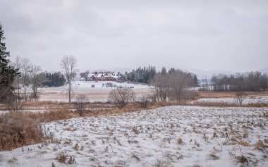 Tranquil winter scene at Shelburne Farms, historic red Inn surrounded by snow-dusted fields, trees, and rolling hills, picturesque display of rural and seasonal charm, Vermont, USA December 2024 clipart