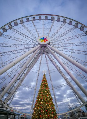 Iconic La Grande Roue dönme dolabı güzel dekore edilmiş Noel ağacı, şenlikli ışıklar ve kış gökyüzü büyülü bir tatil atmosferi yaratır Eski Liman, Montreal, Quebec, Kanada Aralık 2024