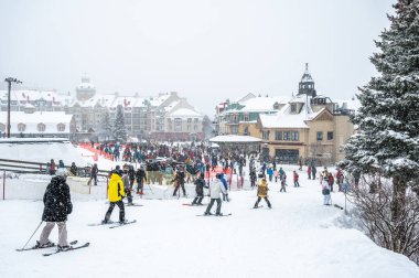 Lively winter scene at Mont-Tremblant ski resort village with skiers, tourists, and colorful architecture during snowfall, perfect travel, lifestyle, and winter activity, Quebec, Canada January 2025 clipart