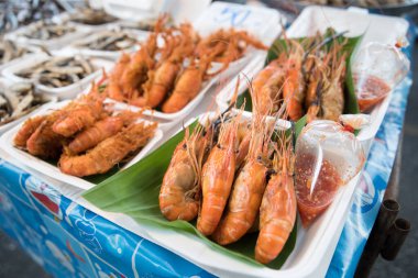 Satılık pakette acı biber soslu karides. Fiyat etiketi arka planda 50 Thb. Tayland, Pattaya, Yeni Naklua Pazarı, 20 Mayıs 2022.