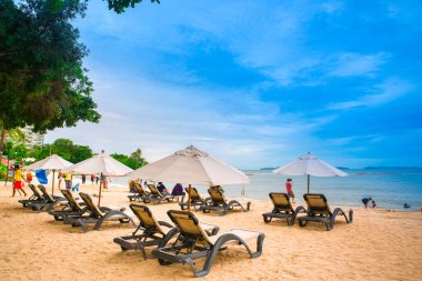 Wong Amat Sahili, Pattaya. Şemsiyeli, güneşli, kumlu bir sahilde, mavi gökyüzüne karşı uzanan bir dinlenme odası. metin için alanı olan resim