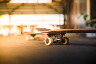 Parlak güneş tarafından aydınlatılan, aşağıdan çekilen, markasız bir kaykayın yakın çekimi, bokeh etkisi. Genç şehir yaşam tarzı konsepti