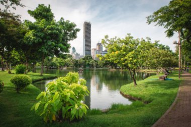 Lumpini Park 'ın gündüz vakti göl ve yeşil bitki örtüsü olan şehir manzarası. Bangkok, Tayland.