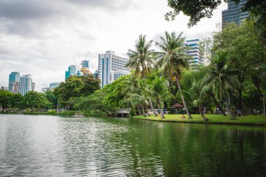 Bangkok, Tayland. 5 Temmuz 2022. Gündüz vakti gökdelenleri, gölleri ve ağaçları olan Lumpini Park 'ın şehir manzarası. Silom bölgesinde şehir merkezi..