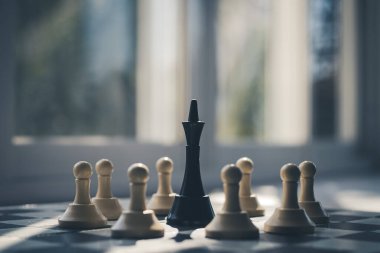 Siyah papaz, satranç tahtasındaki beyaz piyonlarla çevrili. Bir takımın lideri diğer takımın üyeleri tarafından yakalanır. Diktatör kuşatma altında