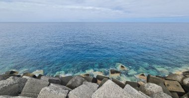 Mavi suyu ve gri taşları olan deniz burnu