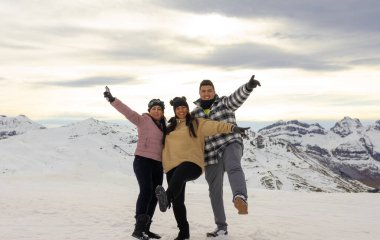 Üç Latin yetişkin, mutlu ve gülümsüyor, Pireneler 'in karına atlıyorlar.