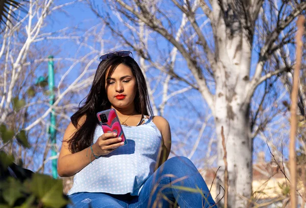 Joven Embarazada Sentada Parque Mirando Celular Pensativa Lleva Ropa Azul —  Fotos de Stock
