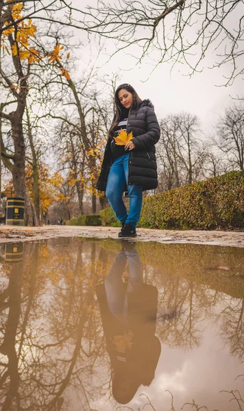 Sonbaharda parkta su yansıtmalı bir kadın.