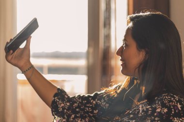 Genç bir kadın evde selfie çekiyor.