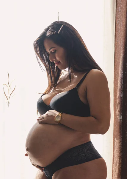 Молодая Беременная Латинская Женщина Смотрит Трогает Свой Живот Черном Нижнем — стоковое фото