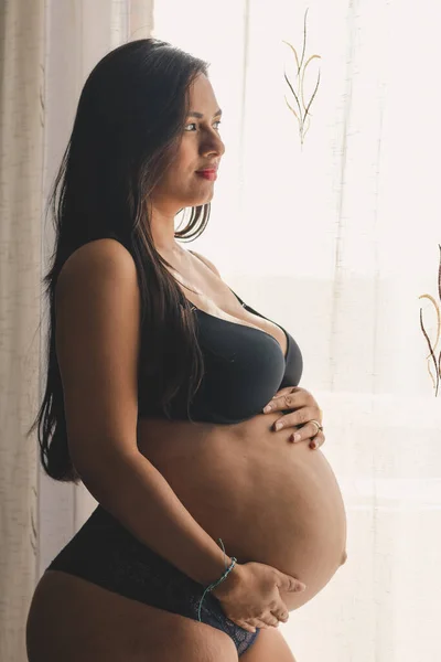 Беременная Молодая Женщина Дотрагивается Живота Черном Нижнем Белье Смотрит Горизонт — стоковое фото