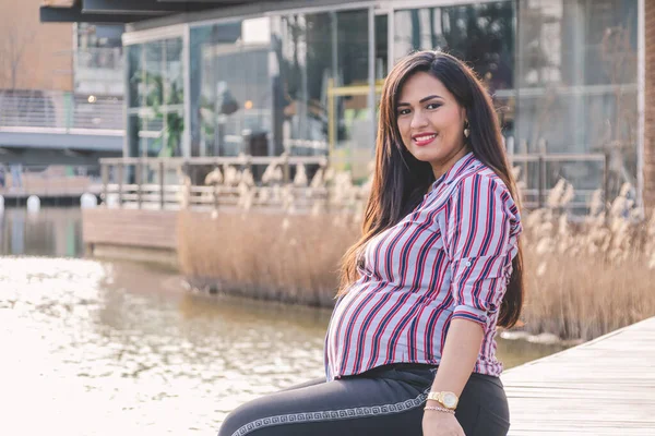 Junge Schwangere Frau Sitzt Auf Der Anklagebank Lächelt Und Blickt — Stockfoto