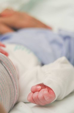 Yeni doğan bebeğin eli hastane yatağında uyurken tutuldu.
