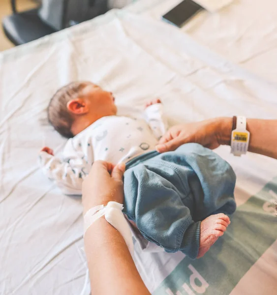 stock image Mother dressing newborn baby in a hospital bed