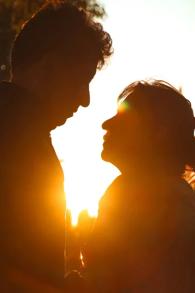 Silhouette of latin couple holding hands and staring at each other at sunset.