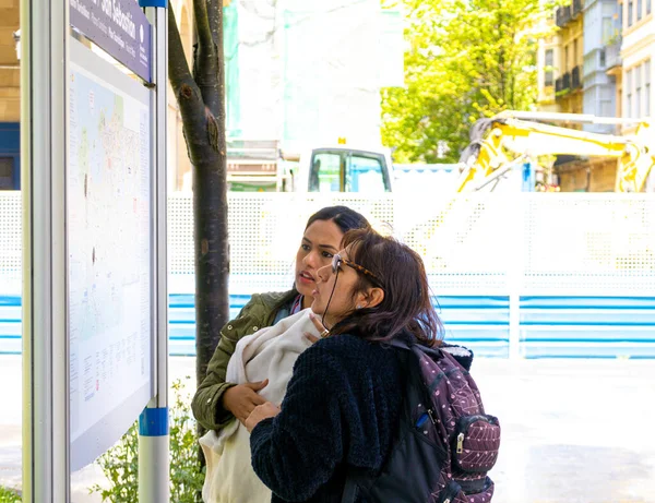 Two latin women on a trip looking at a physical map