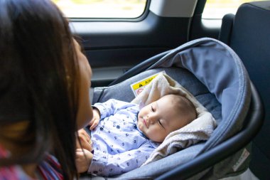 Annem bebek koltuğunda uzanmış bebeğine bakıyor.