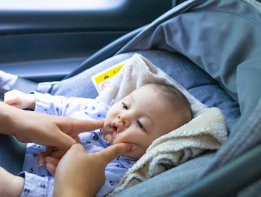 Anne kucağında oturan bebeğini okşuyor.