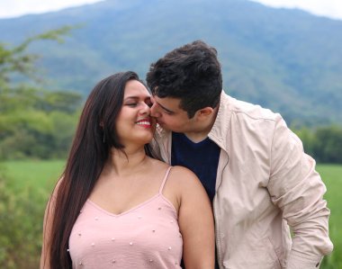 Latin çift birbirine bakıyor ve parkta gülümsüyor.