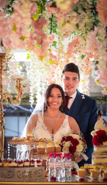 Mutlu bir çift düğün törenlerinde yemyeşil pembe çiçeklere karşı birlikte dururlar..