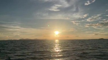 Güneşin batışını ve tekneden gökyüzündeki bulutları görüyorum.