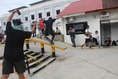 Asyalı bir adam kaykay günü kutlamalarında kaldırımda ya da çıkıntıda kaykay numarası yapıyor. Endonezya - Medan, 21 Haziran 2024