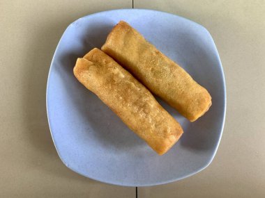 Mavi bir tabakta iki kızarmış börek.