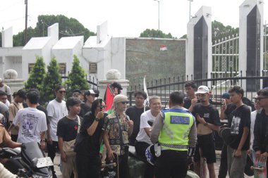 Bir grup Asyalı genç adam bir trafik polisiyle konuşuyor. Endonezya - Medan, 21 Haziran 2024