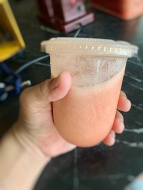 Birisi içinde tamarillo suyu olan plastik bir bardak tutuyor.