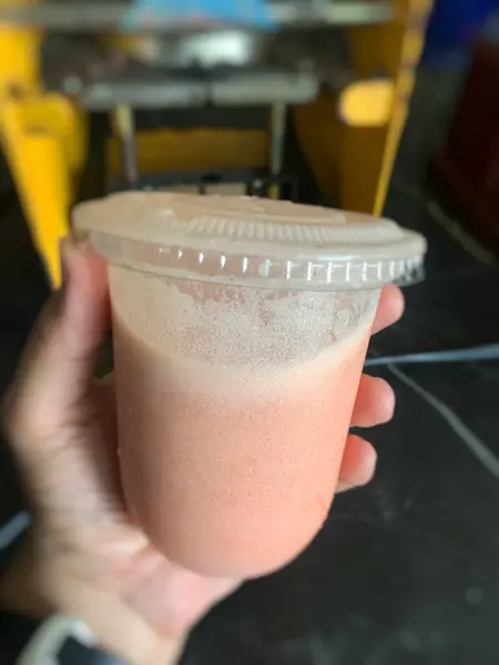 stock image someone is holding a plastic cup with tamarillo juice in it