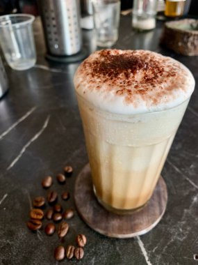 Siyah arkaplanda kahve çekirdekleri olan kapuçino.