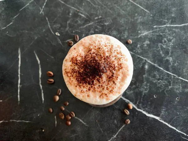 Siyah arkaplanda kahve çekirdekleri olan kapuçino.