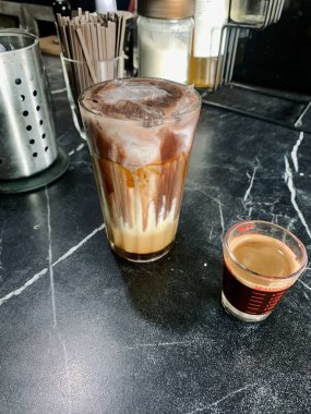 Bir bardak çikolatalı buzlu kahve ve küçük bir fincan kahve..