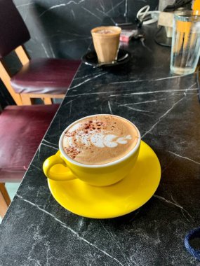 Masanın üzerinde bir fincan sarı cam kapuçino..