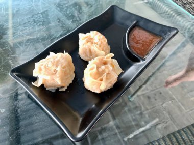 Siyah bir tabakta soslu üç gamsum..