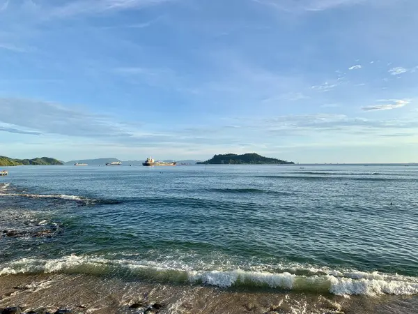 Sahilde dalgalar ve gemiler var.