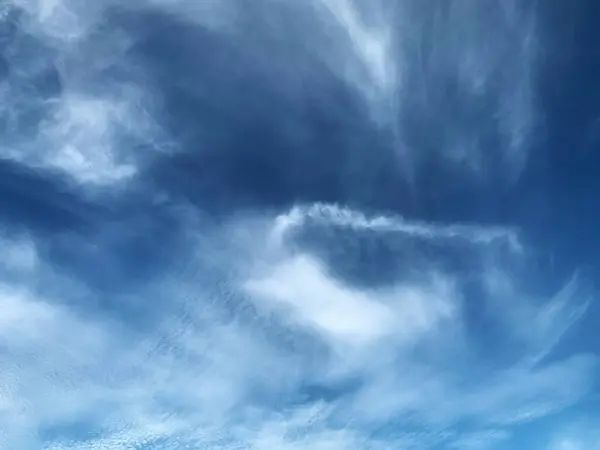 Yumuşak, ince bulutları olan berrak mavi bir gökyüzü yavaşça sürükleniyor, sakin ve huzurlu bir atmosfer yaratıyor.