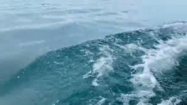 Bir tekne hareket ediyor, geminin önünden küçük dalgalar yapıyor..