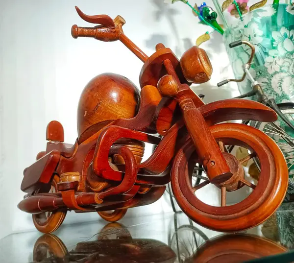 A Miniature Toy Motorbike Made Of Handmade Wood, Placed On A Glass Table
