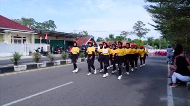MUNTOK, INDONESIA - 14 Eylül 2023: Sarı ve Siyah Üniformalı İlköğretim Öğrencileri, Endonezya 'nın Bağımsızlık Günü Kutlamaları sırasında Bir Yürüyüşe Katılın (Yürüyüş)