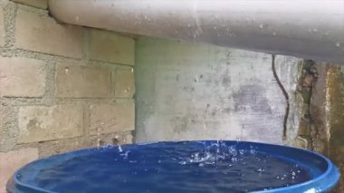 Yavaşça suyla dolu mavi bir davulun çatısından damlayan yağmur damlalarının hareketi